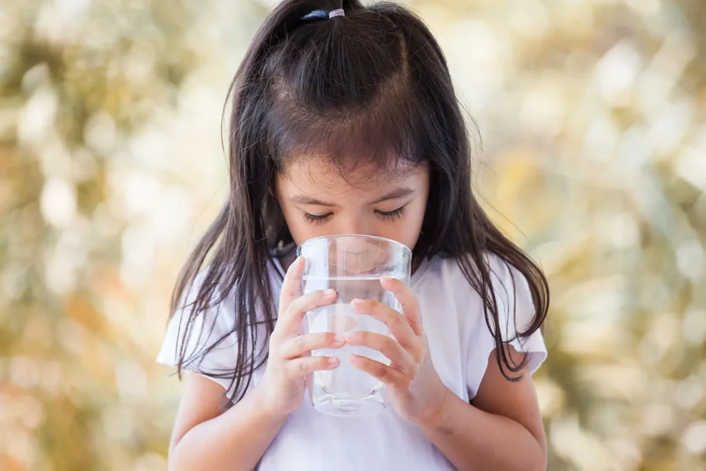 Girl drinking fresh water, showcasing the importance of hydration for oral health and gum health, promoted by Legacy Smiles.