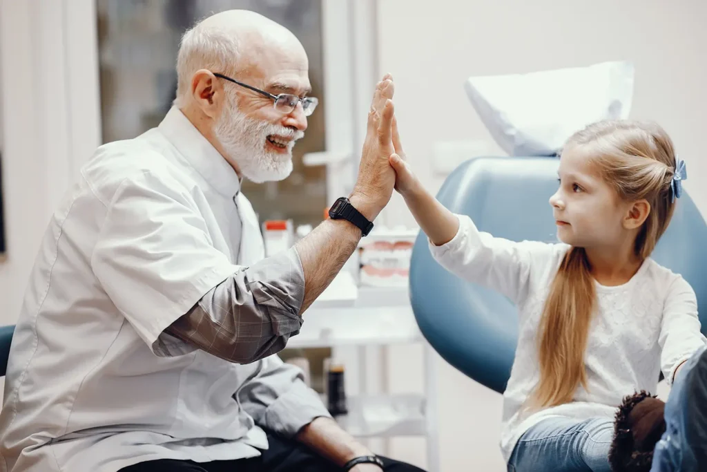Little girl high-fiving a dentist at Legacy Smiles, highlighting excellent oral health and gum health care for children.