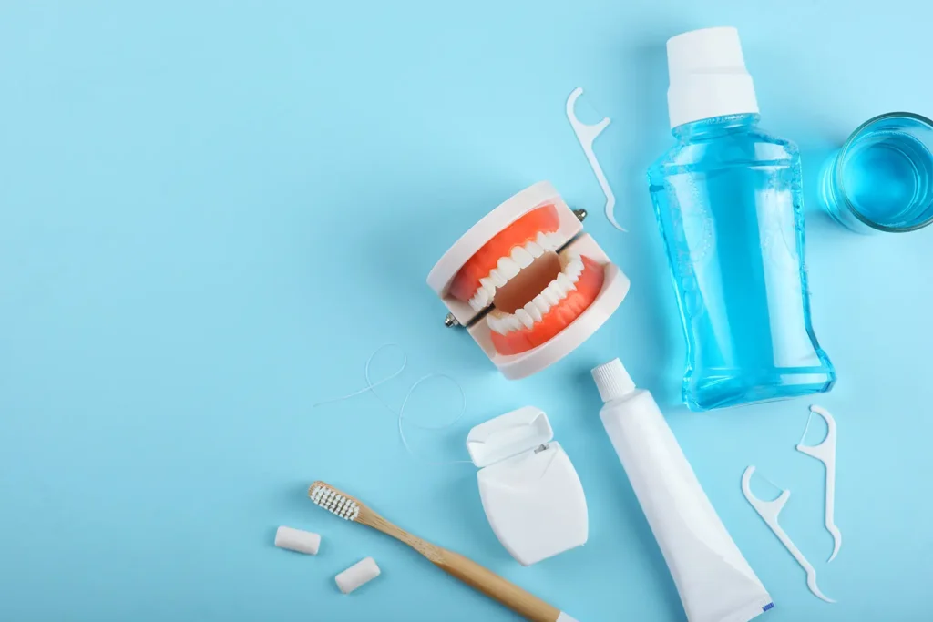 A collection of dental care products, including a dental model, toothbrush, floss, and mouthwash, on a blue background, emphasizing oral hygiene and healthy habits.