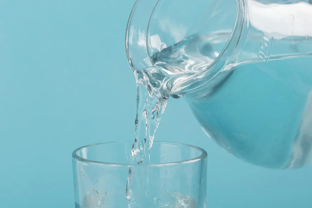 pouring clear water into a glass emphasizing hydration as part of oral hygiene and keeping teeth healthy