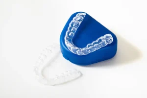 Clear mouth guard on a blue case, illustrating dental protection solutions offered by Legacy Smiles in Billings, MT. Custom-fitted mouth guards are essential for preventing teeth grinding and ensuring optimal oral health.