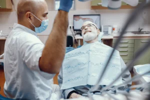 A senior patient smiling while sitting in a dentist's chair during a checkup at Legacy Smiles, highlighting dental care for cavities.